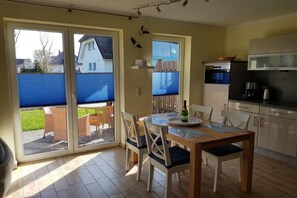 Eine Küche mit Esstisch und Stühlen, einem Kühlschrank und einer Mikrowelle.