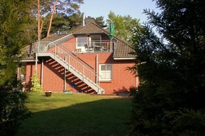 A two-story brick house with a balcony and a staircase leading to the upper floor. - Holiday apartment in Kölpinsee with barbecue (Kölpinsee)