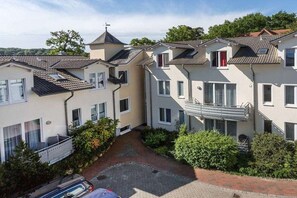Un immeuble résidentiel doté de nombreux balcons, d’une cour intérieure et d’une voiture garée devant.