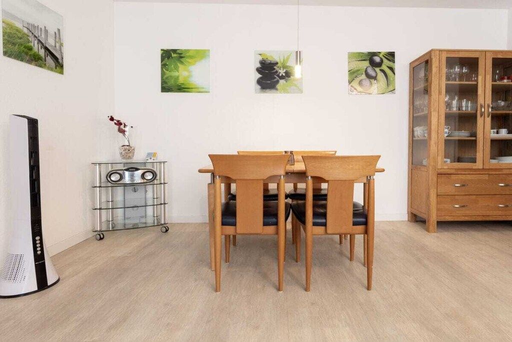 A dining area with a wooden table and chairs, a cabinet with glass doors, and wall art.