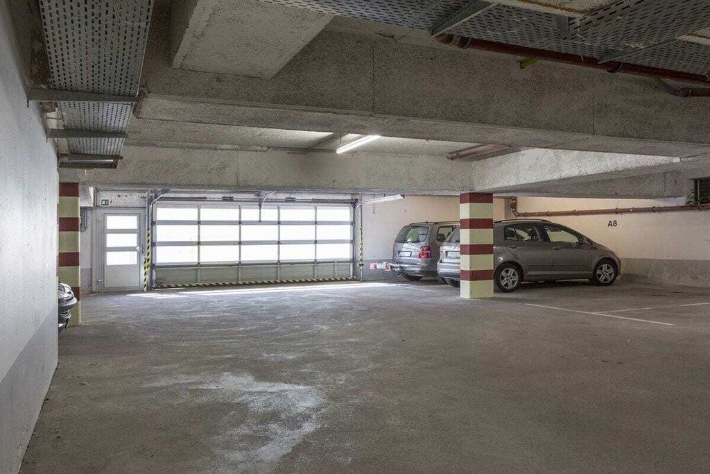 Un aparcamiento con pilares de hormigón, una puerta de garaje y un coche dentro.