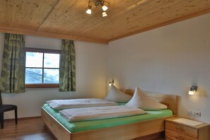 Une pièce avec un plafond en bois, un lit avec deux oreillers, une table de chevet et une chaise.