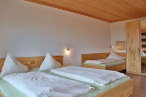 Habitació d'hotel amb dos llits, ambres de fusta, una làmpada penjada a la paret i sostre de fusta.