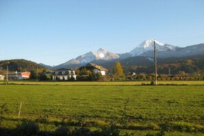A rural landscape with a house, a field, and a mountain in the background. - Holiday apartment with 1 bedroom (Faak am See)