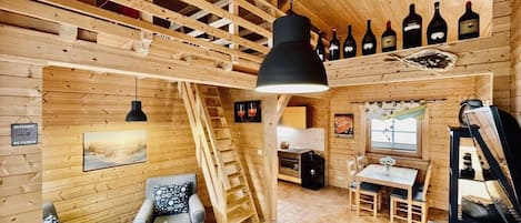 A wooden interior with a dining area, a staircase, and wine bottles displayed on the wall.