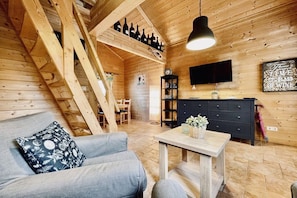 A cozy wooden interior with a sofa, a table, a TV, and a wine rack. - Log cabin Seagull's nest (Dierhagen)