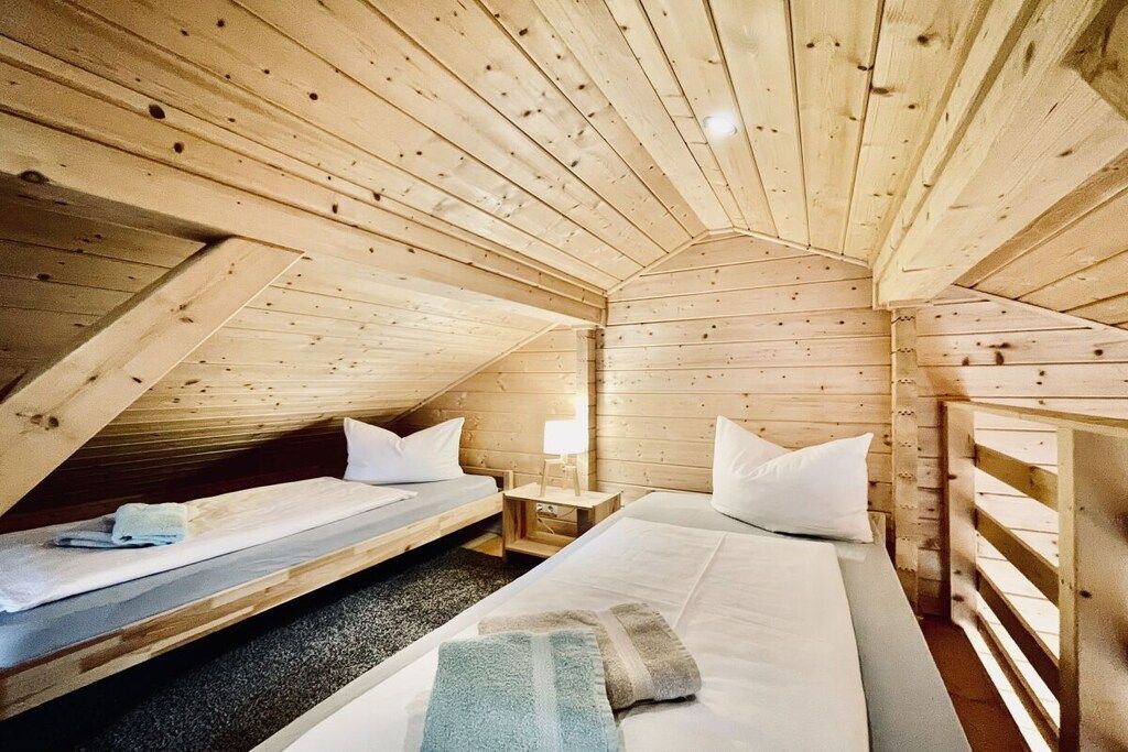 Eine Holzhütte mit zwei Betten, einem kleinen Tisch und einer Lampe.