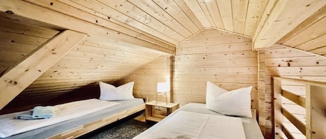 Una cabaña de madera con dos camas, una mesita y una lámpara.