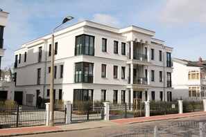 A modern multi-story building with balconies, a gated entrance, and a clear sky. - Villa Poseidon 14 - Atlantis Binz (Ostseebad Binz)