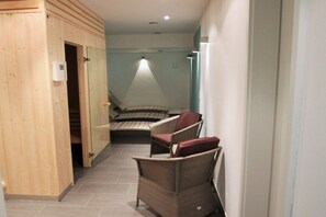A hallway with a bed, two chairs, and a wooden door. - Villa Poseidon 14 - Atlantis Binz (Ostseebad Binz)