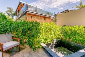 A modern outdoor space with a wooden bench, a glass-enclosed structure, and lush greenery. - Luxury & Serenity 2bd apt retreat, 1 km from beach (tulum)