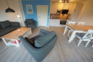 A compact living space with a sofa, a dining table, and a kitchenette. - Holiday home in Prerow with swimming pool (Prerow)
