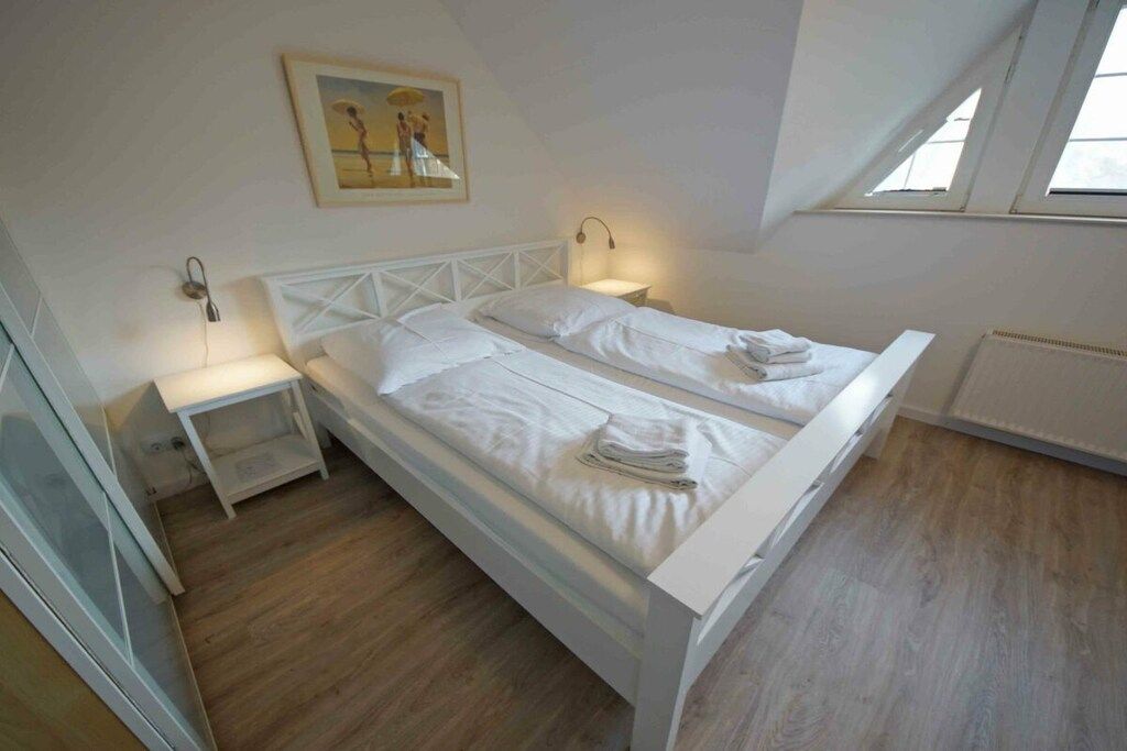 Une chambre à coucher avec un lit, des tables de chevet, un tableau et une fenêtre.