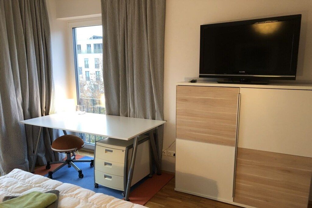 Ein Hotelzimmer mit Bett, Schreibtisch, Stuhl, Fernseher und Fenster.