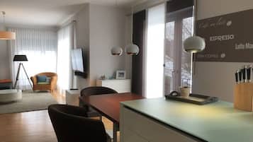 Ein modernes Wohnzimmer mit Essbereich, einem Flachbildfernseher und einer Wand mit Schriftzügen zum Thema Kaffee.