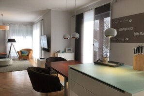 Ein modernes Wohnzimmer mit Essbereich, einem Flachbildfernseher und einer Wand mit Schriftzügen zum Thema Kaffee.