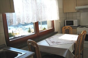 A kitchen with a dining table set for two, a microwave, and a stove. - Holiday home with 1 bedroom (Breitenbrunn OT Rittersgrün)