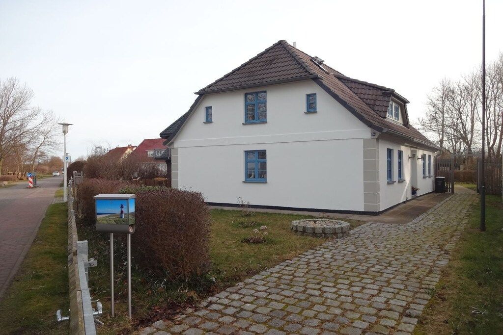 Ein zweistöckiges Haus mit Ziegeldach, befestigter Auffahrt und Briefkasten.