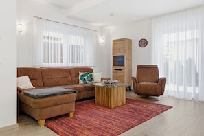 A modern living room with a brown sofa, a glass coffee table, a brown armchair, and a wooden cabinet. - Holiday apartment in Zinnowitz with Wi-Fi (Zinnowitz)