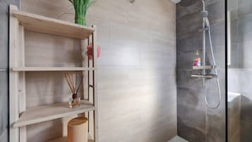 Een moderne badkamer met een douche, een houten plankje met decoratieve spullen en een toilet.