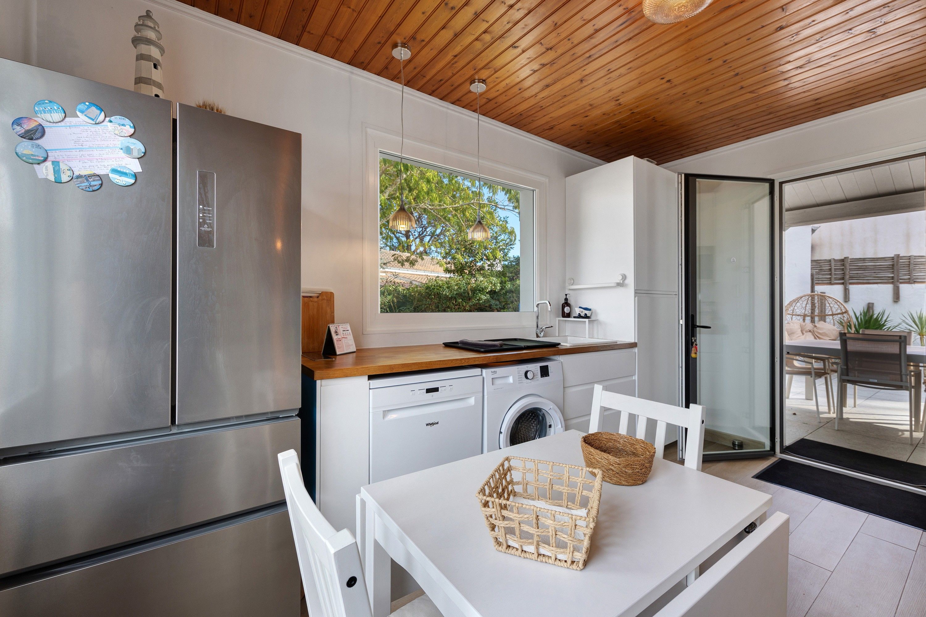 Une cuisine moderne dotée d’appareils électroménagers en acier inoxydable, d’un plafond en bois et offrant une vue sur la verdure environnante.