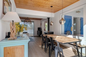 Un comedor con una mesa de madera, sillas negras y una lámpara colgante moderna.