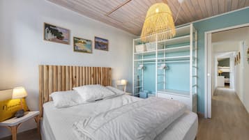 Een slaapkamer met een bed, een nachtkastje, een lamp, een kledingkast en een hanglamp.