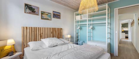 Ein Schlafzimmer mit einem Bett, einem Nachttisch, einer Lampe, einem Kleiderschrank und einer Pendelleuchte.