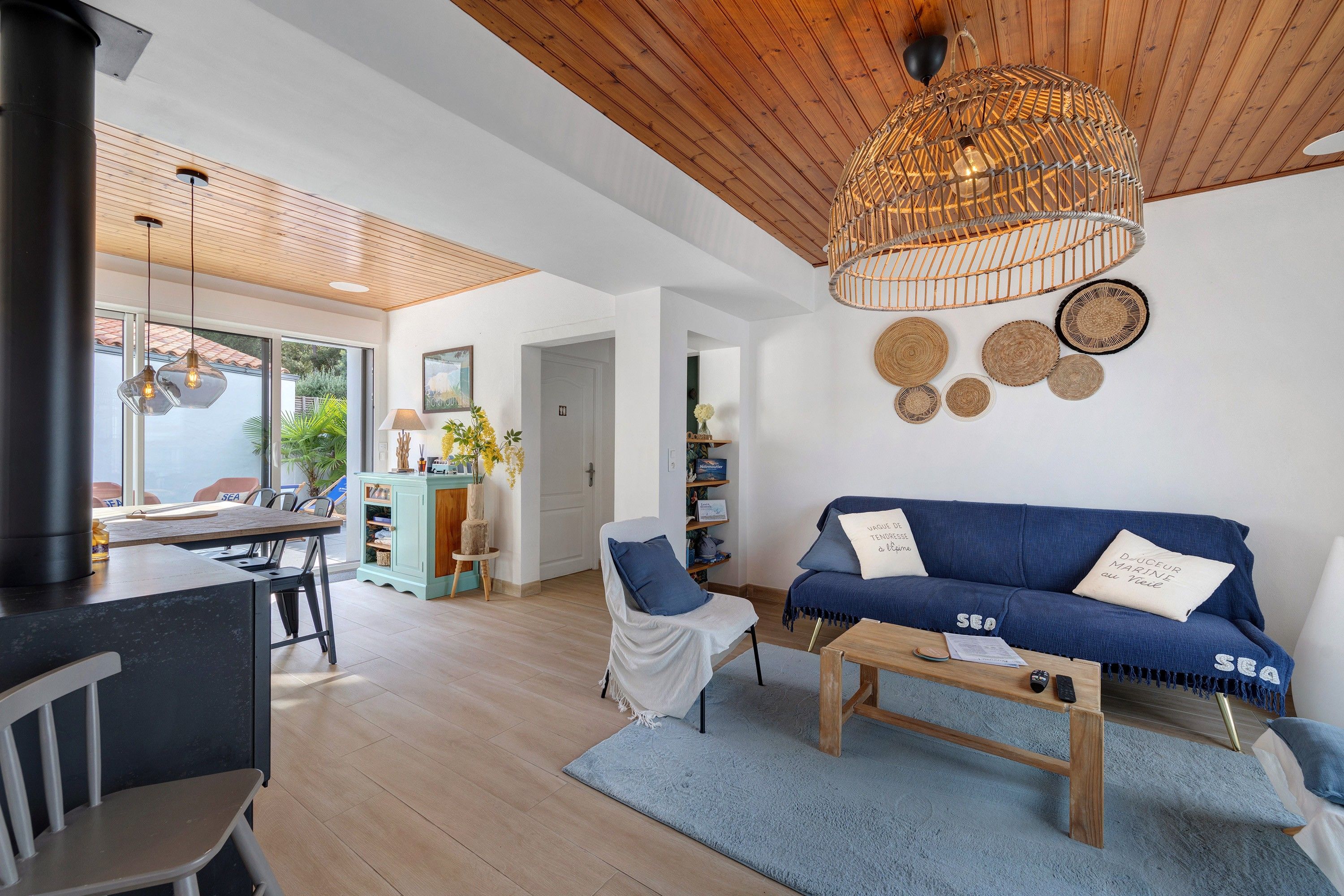 Una sala de estar moderna con un sofá azul, una mesa de centro de madera y una lámpara colgante de ratán.