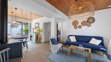 Una sala de estar moderna con un sofá azul, una mesa de centro de madera y una lámpara colgante de ratán.