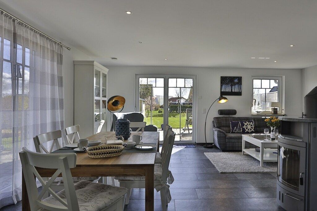 A modern living room with a dining area, a fireplace, and large windows.