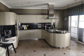 A modern kitchen with a curved island, stainless steel appliances, and a large window providing natural light. - Holiday home with 1 bedroom (Fuhlendorf)