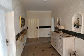 A hallway with a white door, a framed picture, a cabinet with drawers, and a wall-mounted light fixture. - Holiday home with 1 bedroom (Fuhlendorf)