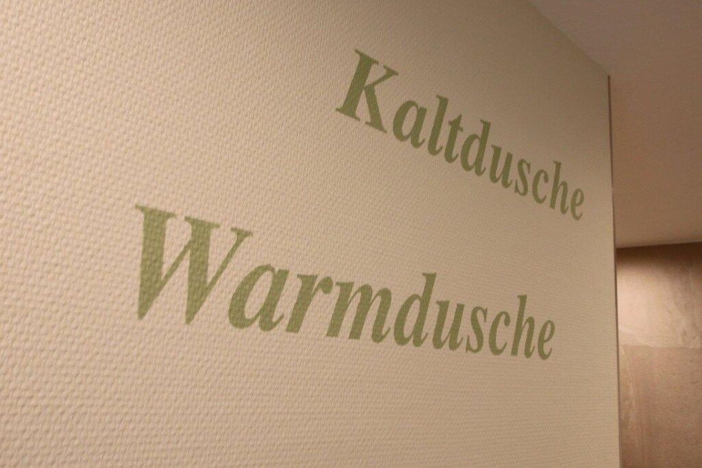 A wall with the text 'Kaltdusche' and 'Warmdusche' indicating cold and warm showers.