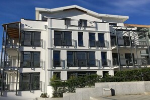 Ein mehrgeschossiges Wohngebäude mit Balkonen und einer Treppe, bewölkter Himmel.