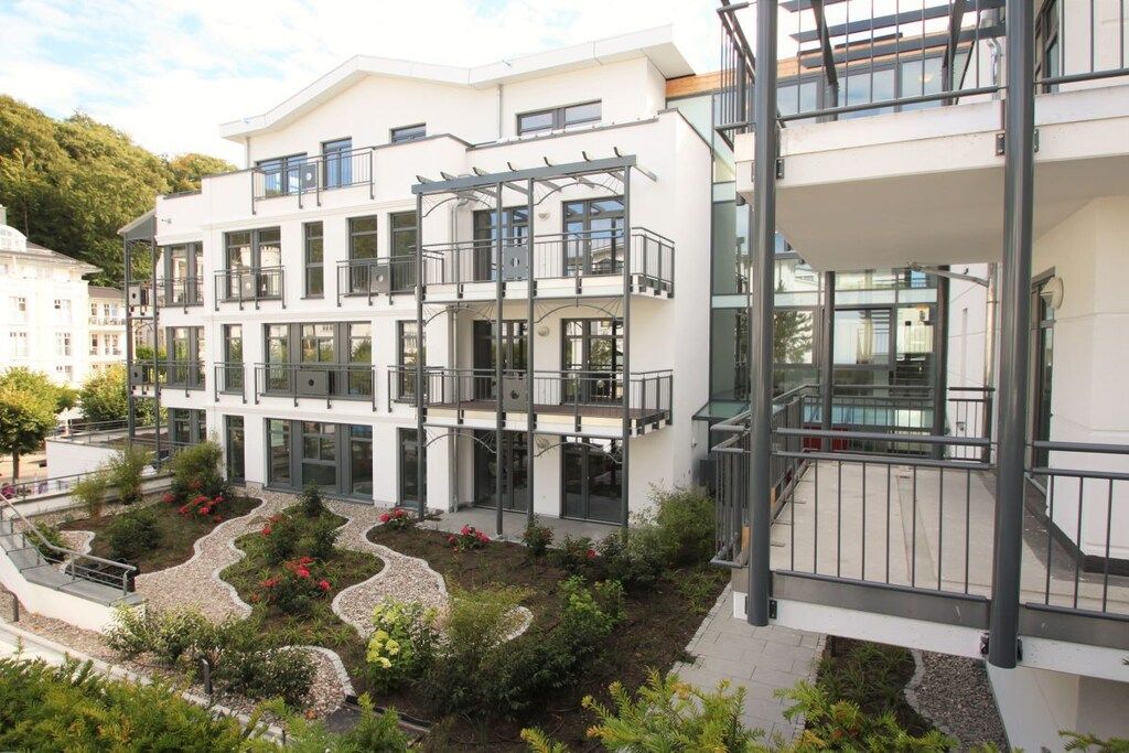 A multi-story residential building with balconies, a landscaped garden, and a modern architectural design.