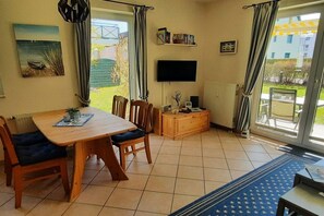 Ein Essbereich mit Tisch und Stühlen, einem Fernseher und Blick ins Freie.