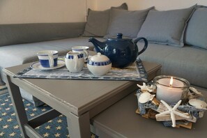 Ein gemütlicher Sitzbereich mit einem Tisch, der für Tee gedeckt ist, einem blauen Teekessel und einer Kerze, umgeben von Muscheln und Seesternen.