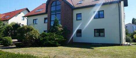 Asuinrakennus, jossa on punatiilinen katto, useita ikkunoita ja hyvin hoidettu nurmikko.