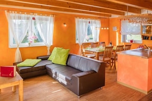 A cozy living area with a sofa, dining table, and kitchen counter. - Holiday home in Bannemin with swimming pool (Bannemin)