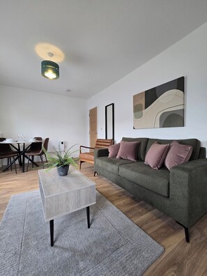Una sala de estar moderna con un sofá gris, una mesa de centro y un comedor con una mesa y sillas.