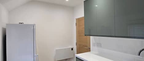 Una cocina compacta con refrigerador empotrado, un lavamanos y piso de madera.