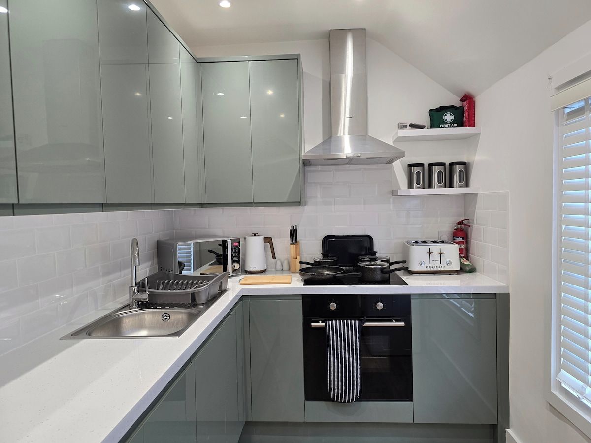 A modern kitchen with a stainless steel sink, a built-in oven, and a range hood.
