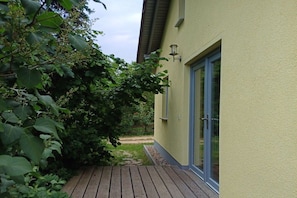 A house with a wooden deck, a glass door, and a light fixture on the exterior wall. - Burkhardt Holiday Home (Neustrelitz)