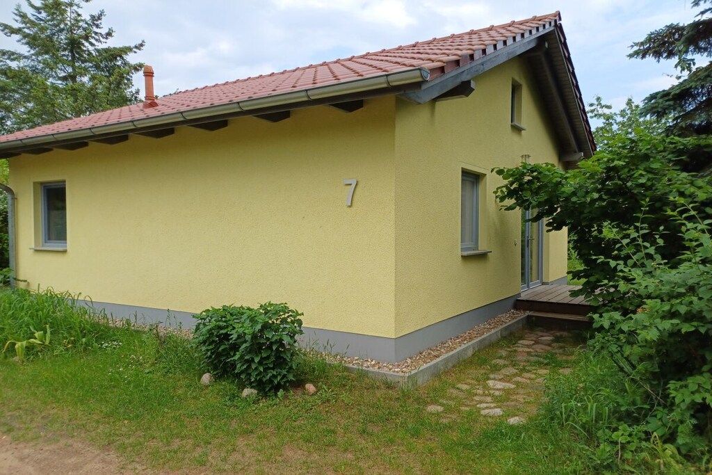 A yellow building with a red-tiled roof, a number '7' on the side, and a small porch with steps.
