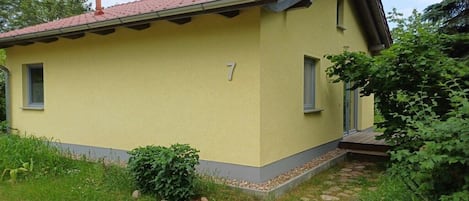 A yellow building with a red-tiled roof, a number '7' on the side, and a small porch with steps.