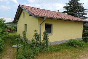 A single-story yellow building with a red-tiled roof, a small window, and a door. - Burkhardt Holiday Home (Neustrelitz)