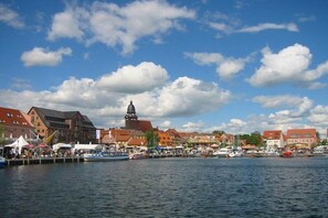 Eine Stadt am Wasser mit Gebäuden, einem markanten Kirchturm und Booten, die an der Küste liegen.
