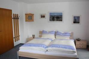 Ein Schlafzimmer mit einem Bett, einem Holzschrank, einem Nachttisch und Bildern an der Wand.