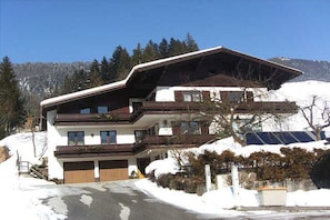 Ein mehrstöckiges Gebäude mit einem geneigten Dach, einer Garage und Blick auf eine verschneite Landschaft.